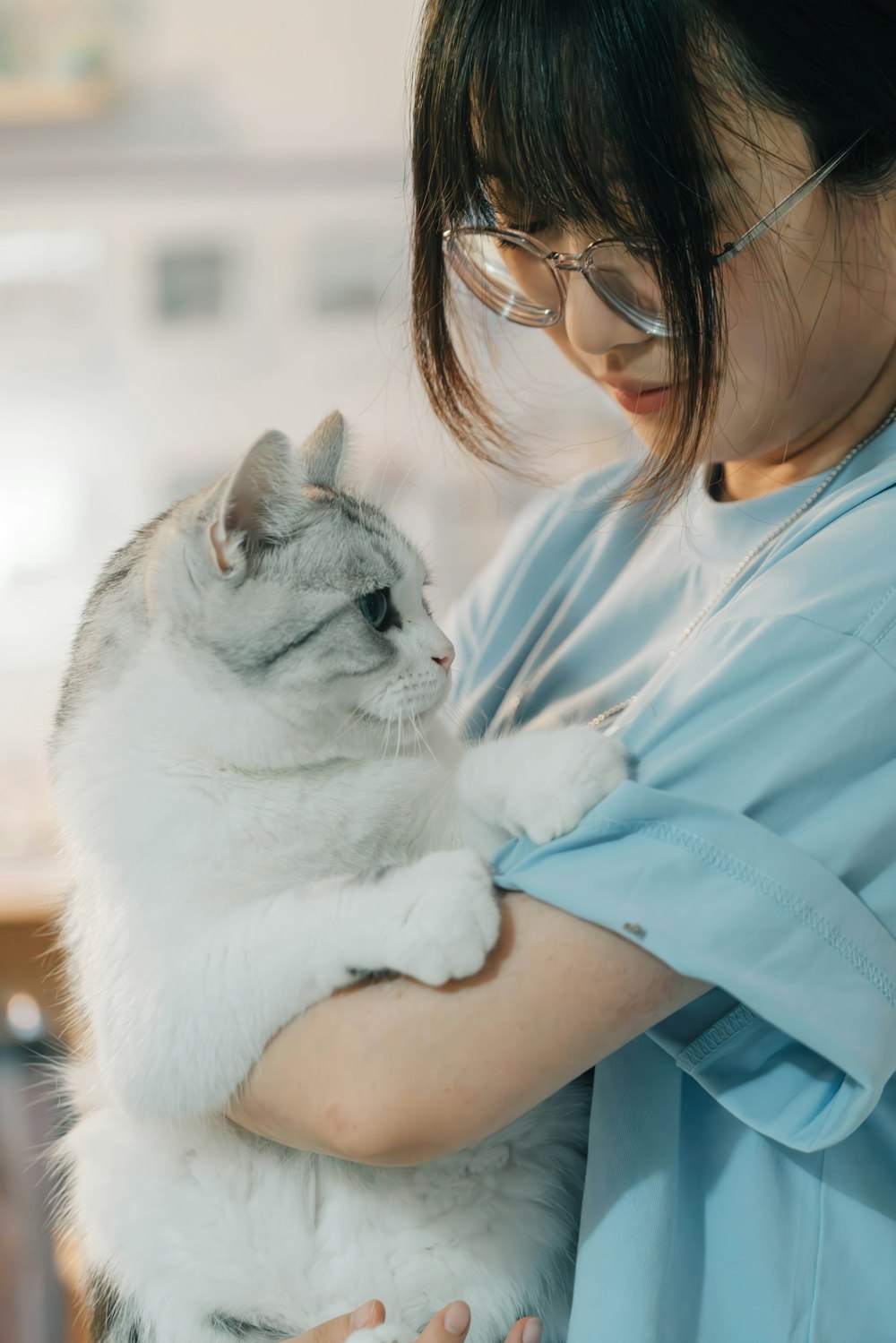 A vet tech in scrubs holding a white cat